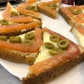 Cool sandwich with red fish and olives on a white plate