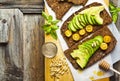 Sandwich with rye bread on old wooden table: avocado, yellow tom