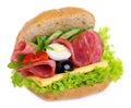 Sandwich with salami cheese egg salad cucumbers onions olives and tomatoes