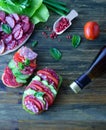 Sandwich with salami with tomatoes and cucumbers next sliced salami and tomato and Basil leaves with salad and a bottle of wine Royalty Free Stock Photo