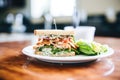 a sandwich with sliced stuffed chicken, crisp lettuce, and feta spread on multigrain bread