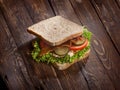 Sandwich with smoked meat, green salad, fresh tomatoes and pickled cucumbers, on kitchen wooden table background Royalty Free Stock Photo