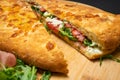 Sandwich with smoked pork ham, mozzarella, tomatoes and arugula salad on wooden plate on black background Royalty Free Stock Photo