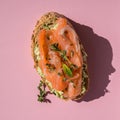 Sandwich with smoked salmon and avocado on a pink background, top view. Sandwich with salmon slices on pink.