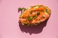 Sandwich with smoked salmon and avocado on a pink background, top view. Sandwich with salmon slices on pink.