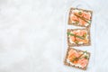 Sandwich with smoked salmon and cream cheese on thin multi seed crispbread, garnished with green onion and olives, horizontal,
