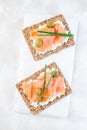 Sandwich with smoked salmon and cream cheese on thin multi seed crispbread, garnished with green onion and olives, vertical, top