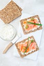 Sandwich with smoked salmon and cream cheese on thin multi seed crispbread, garnished with green onion and olives, vertical, top
