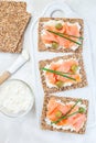 Sandwich with smoked salmon and cream cheese on thin multi seed crispbread, garnished with green onion and olives, vertical, top