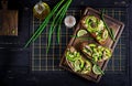 Sandwich - smorrebrod with sprats, avocado and cream cheese on wooden board. Royalty Free Stock Photo