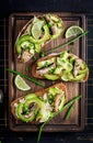 Sandwich - smorrebrod with sprats, avocado and cream cheese on wooden board. Royalty Free Stock Photo