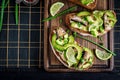 Sandwich - smorrebrod with sprats, avocado and cream cheese on wooden board. Royalty Free Stock Photo