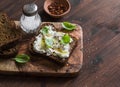 Sandwich with soft cheese, olive oil and basil, served on olive cutting board on dark wooden surface. Royalty Free Stock Photo