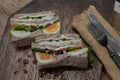 Sandwich stuffed with chicken breast, cheese, boiled eggs and fresh vegetables serve with fork and knife on wooden plate Royalty Free Stock Photo