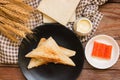 Sandwich stuffed with salad sauce and crab stick in black dish on wooden table