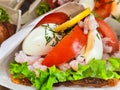 Sandwich on toasted rye bread with herbs, shrimp, eggs and tomatoes closeup