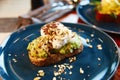 Sandwich, white bread with avocado herbs and spices, with a soft-boiled egg, lies on a blue plate Royalty Free Stock Photo