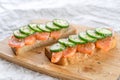 Sandwiches with bread, fresh fish and sliced cucumbers with spices on wooden tray Royalty Free Stock Photo