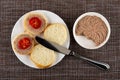 Sandwiches from bread, liver pate and tomato in plate, knife, bowl with liver pate on mat. Top view Royalty Free Stock Photo