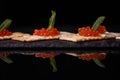 Sandwiches of cracker canapes with red caviar and butter and a leaf of green mint on a plate of slate. Seafood, red caviar.