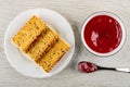 Sandwiches from crackers with flax seeds and jam in plate, bowl with jam, spoon on wooden table. Top view Royalty Free Stock Photo