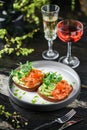 Sandwiches with cream cheese, avocado, slices salmon, red fish caviar and microgreens on plate over table with drinks. Healthy Royalty Free Stock Photo