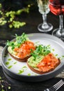 Sandwiches with cream cheese, avocado, slices salmon, red fish caviar and microgreens on plate over table with drinks. Healthy Royalty Free Stock Photo
