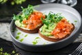 Sandwiches with cream cheese, avocado, slices salmon, red fish caviar and microgreens on plate over table with drinks. Healthy Royalty Free Stock Photo