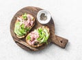Sandwiches with cream cheese, avocado and tuna fish on wooden cutting board on white background, top view. Healthy breakfast Royalty Free Stock Photo