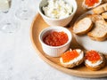 Sandwiches with cream cheese and red caviar on a large wooden tray and ingredients in bowls