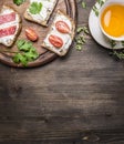 Sandwiches with curd cheese with parsley, cherry tomatoes and salmon on a cutting board and a cup tea with thyme border ,place