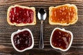 Sandwiches with currant jam, apricot jam, spoon, bowls with jam on table. Top view