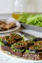 Sandwiches with fried eggplant, fresh tomato, lettuce, dill and garlic on a dish. Lettuce, olive oil, knife on the kitchen table Royalty Free Stock Photo