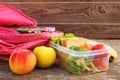 Sandwiches, fruits and vegetables in food box, backpack on old wooden background Royalty Free Stock Photo