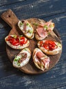 Sandwiches with goat cheese, anchovies, roasted peppers, ham on a wooden rustic board. Royalty Free Stock Photo