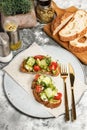 Sandwiches with guacamole sauce and fresh vegetables on a round plate. Toasts with avocado, cucumber, cherry tomatoes and herbs.