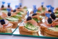 Sandwiches with ham, cucumber, olive on blue skewer with a heart, on a mirror surface, event catering