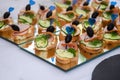 Sandwiches with ham, cucumber, olive on blue skewer with a heart, on a mirror surface, event catering