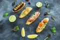 Sandwiches with prawn, salmon fish, mushroom and limes on dark table. Tasty food