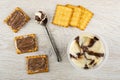 Sandwiches with chocolate-dairy paste, spoon and jar with paste, cookies on wooden table. Top view