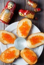 Sandwiches with red caviar of salmon fish. A glass of vodka, matryoshka. The concept of Russian tradition. Flat Lay. Vertical