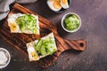 Sandwiches with ricotta, cucumber slices, boiled egg and sesame seeds on a board top view