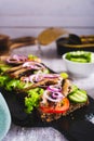 Sandwiches on rye bread with tomatoes, cucumber, sprats and onions on slate vertical view Royalty Free Stock Photo