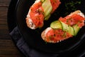 Sandwiches. Salmon toast with cream cheese, cucumber, black sesame and microgreens on old wooden table background. Seafood. Health