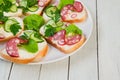 Sandwiches with sausage and greens on a plate on white wooden ta