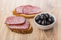 Sandwiches with smoked sausage and bowl with black olives Royalty Free Stock Photo