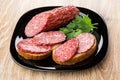 Sandwiches with smoked sausage and parsley in black plate Royalty Free Stock Photo