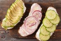 3 sandwiches with soft cheese, cucumber and avocado slices, red onion on a wooden , top view Royalty Free Stock Photo