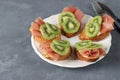 Sandwiches with soft cheese, jamon and kiwi on a white plate. Delicious and healthy breakfast