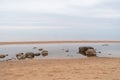 Sandy beach of  Baltic sea covered with big stones on cloudy spring morning. Royalty Free Stock Photo
